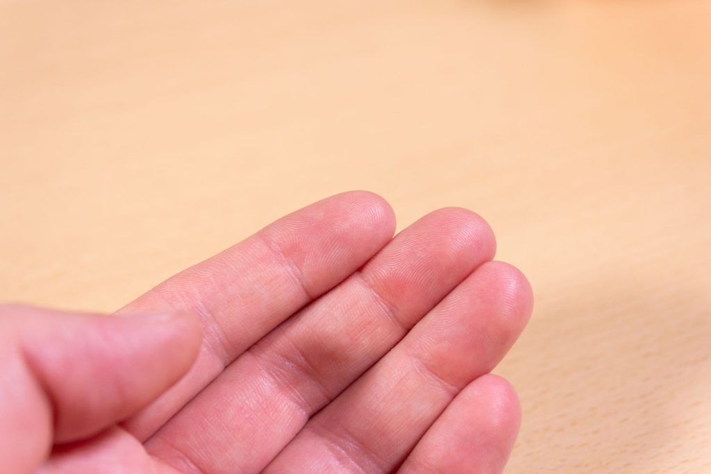 Image shows a hand on a desk.